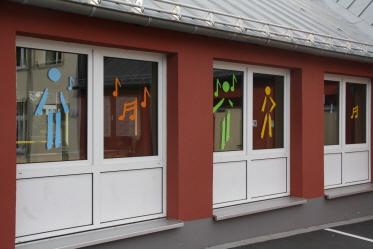 Foto der Fenster des Musikraums mit den neuen Schullogofiguren als Verzierung